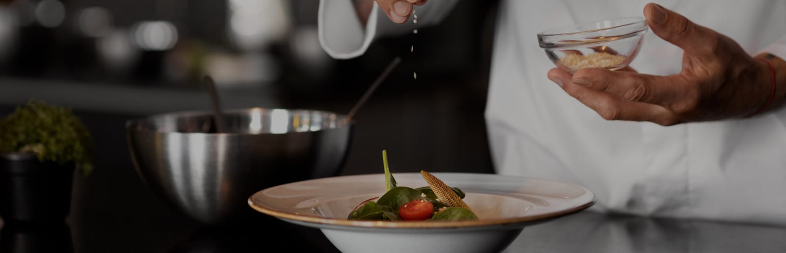 Le mani di un cuoco completano un piatto di insalata nella cucina di un ristorante